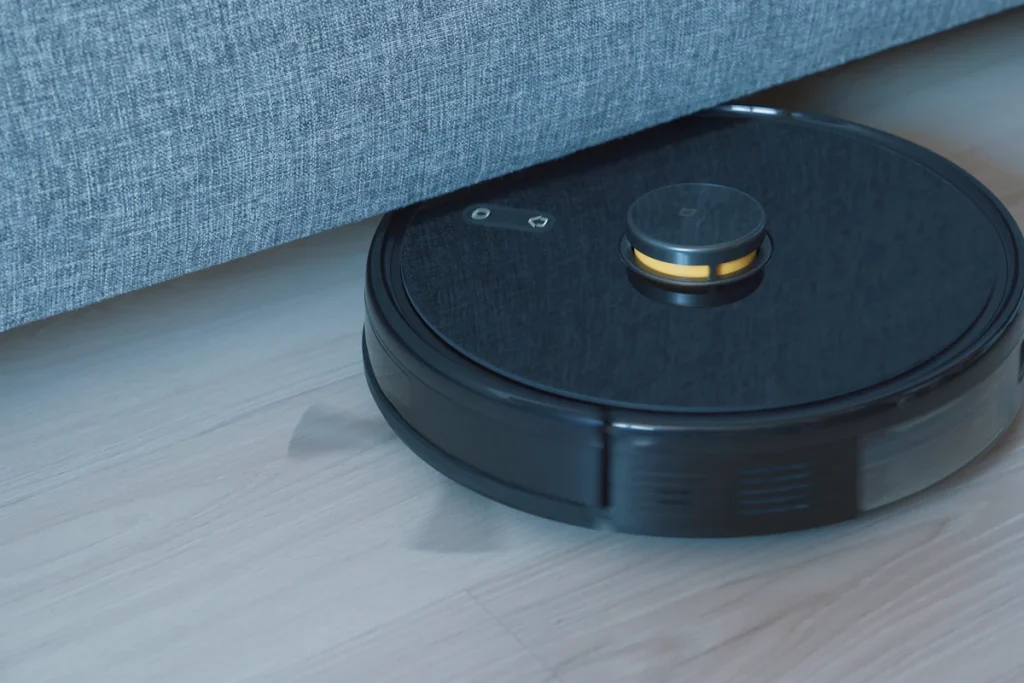 Robot aspirateur noir posé sur un parquet en bois